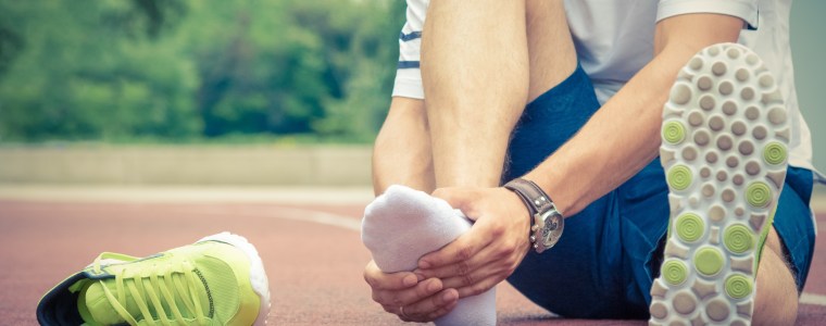 Photograph of a tennis player grasping his injured foot
