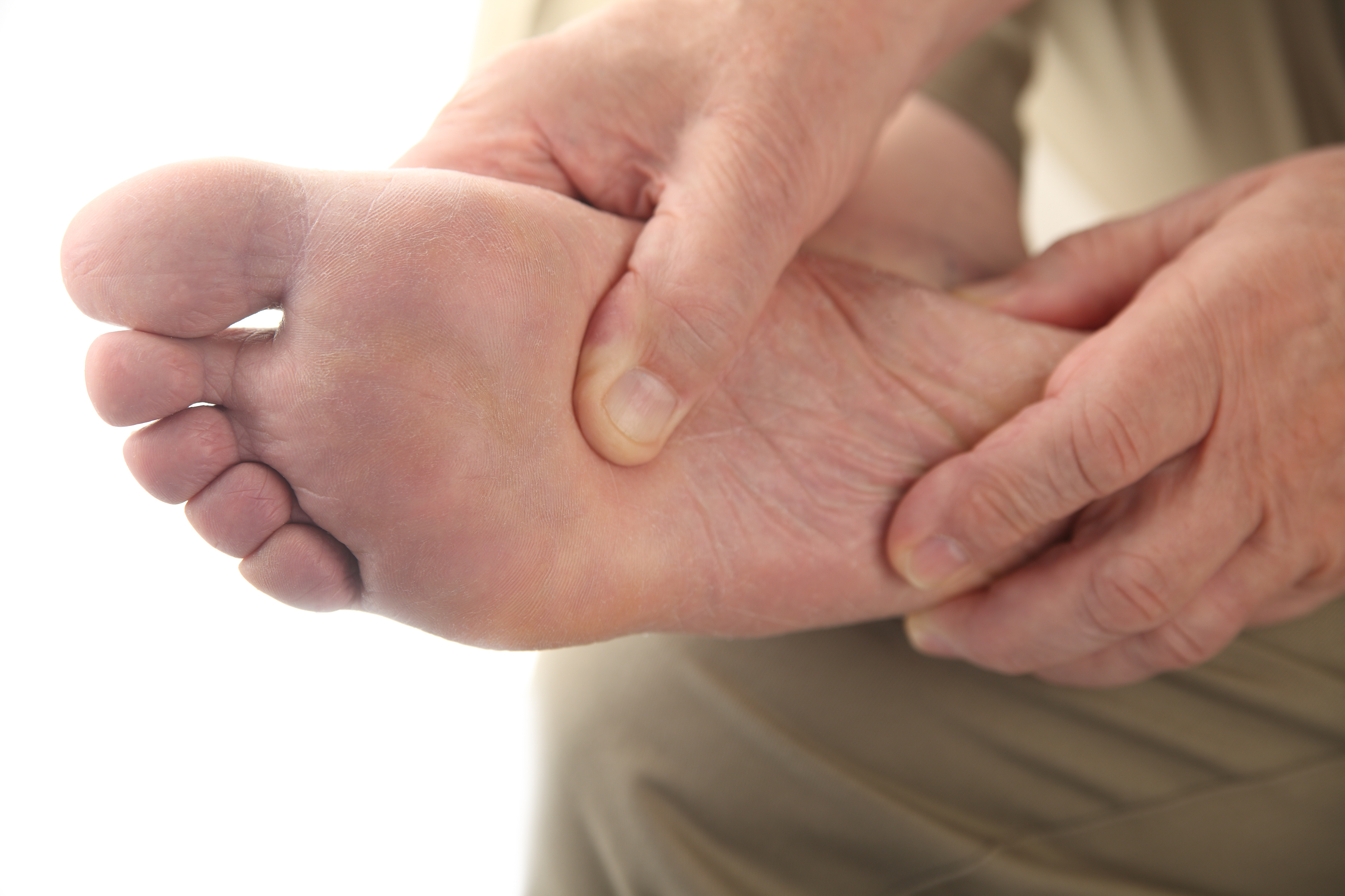 Photograph of elderly man checking his aching foot, close up