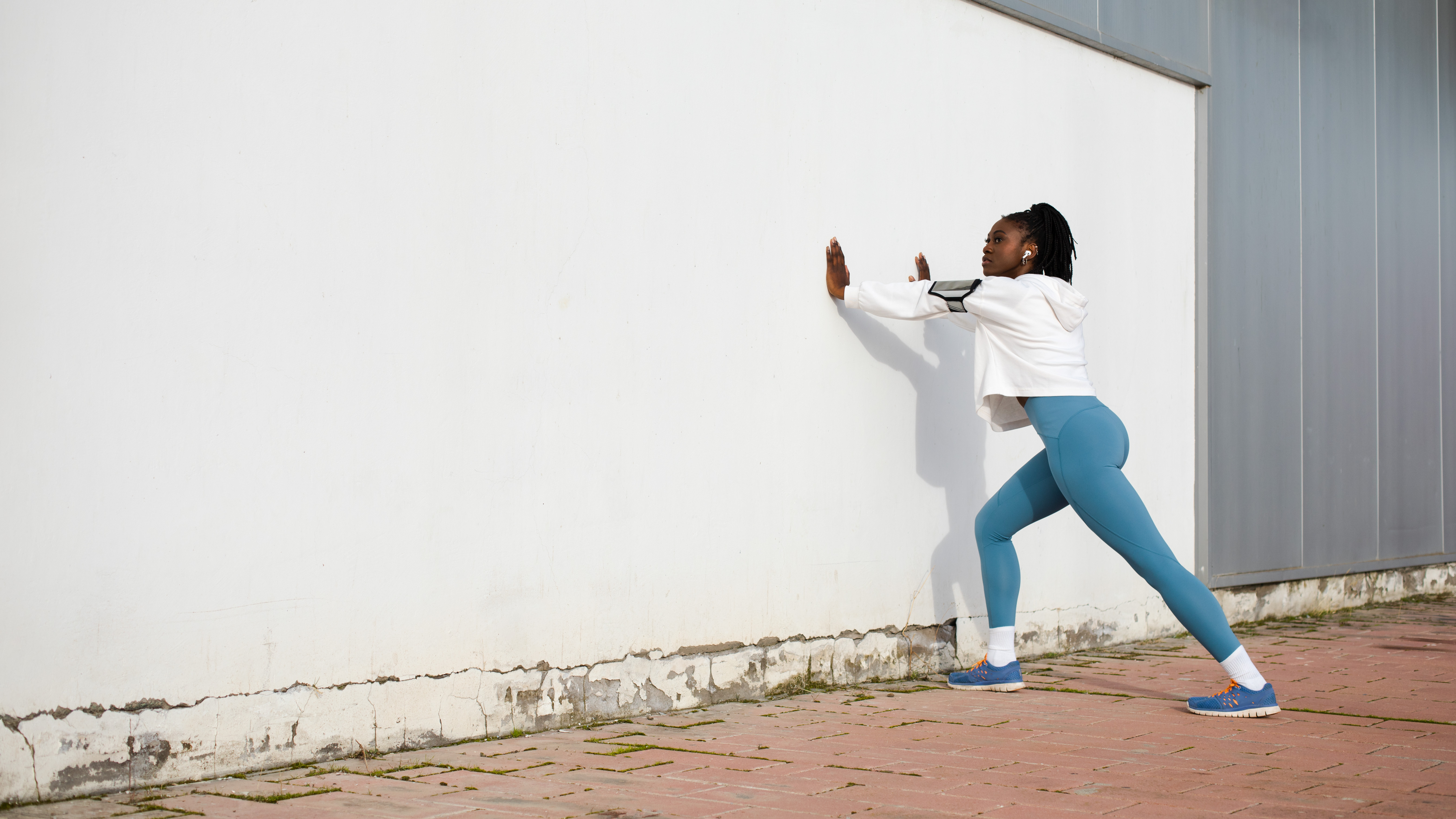 Photograph of female athlete training outside; stretching her calf muscles before a run.