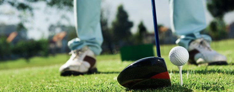Golfer hitting driver club on course for tee shot